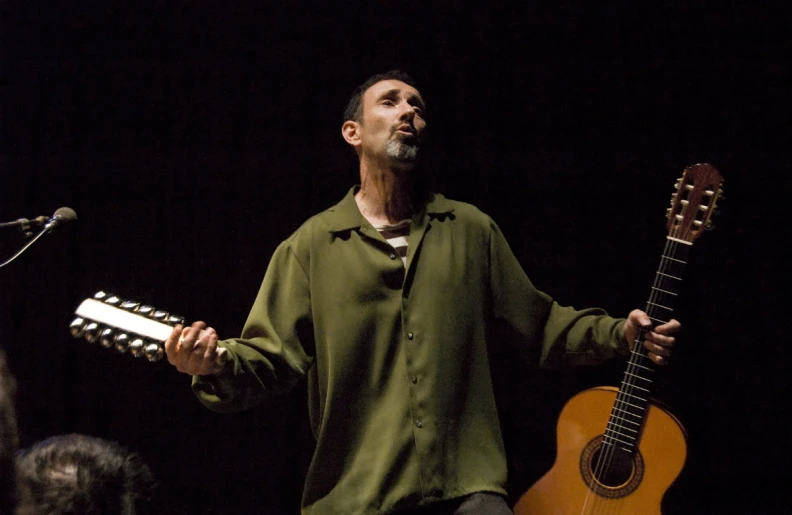 a man standing in front of microphones holding an instrument