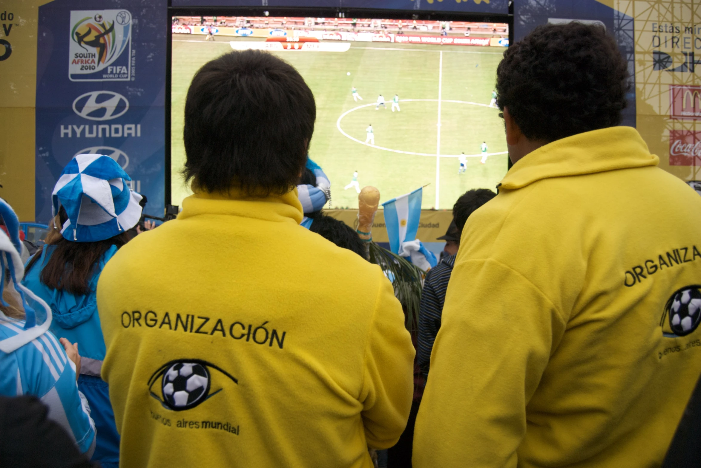 people in yellow and blue sweatsuits watching soccer on tv