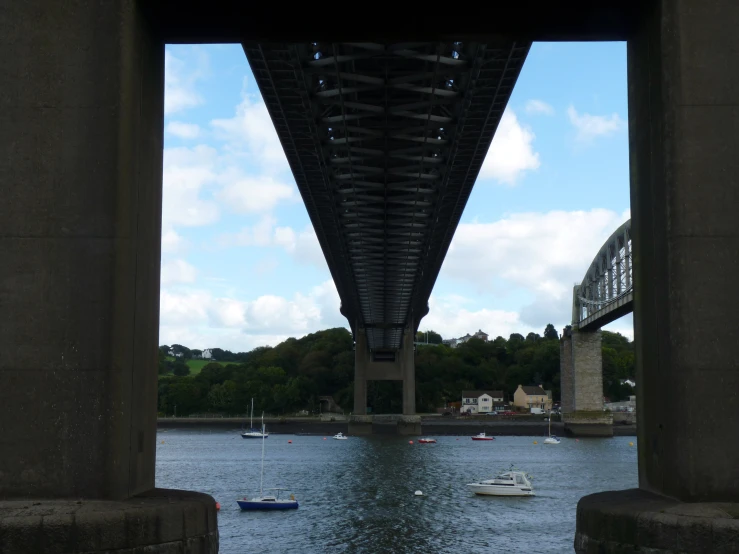 a group of small boats floating underneath a bridge