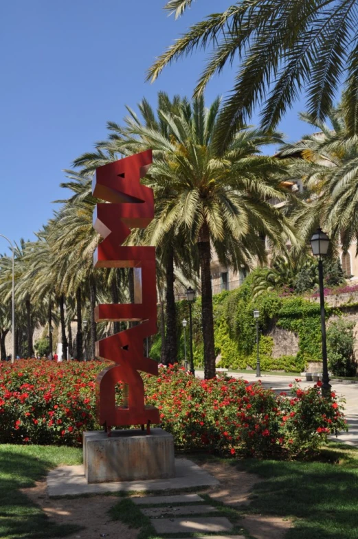 a sculpture sitting in front of a group of trees and flowers