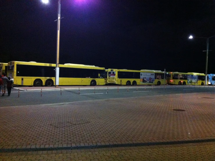 a row of yellow buses sit in the lot