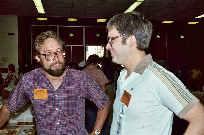 two men stand next to each other and laugh