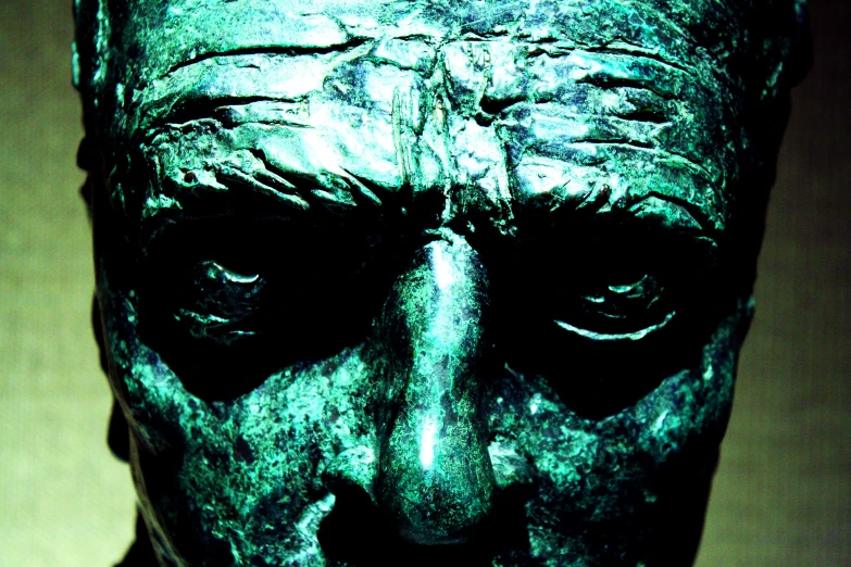 an artistic bronze statue depicting a person with one eye half closed