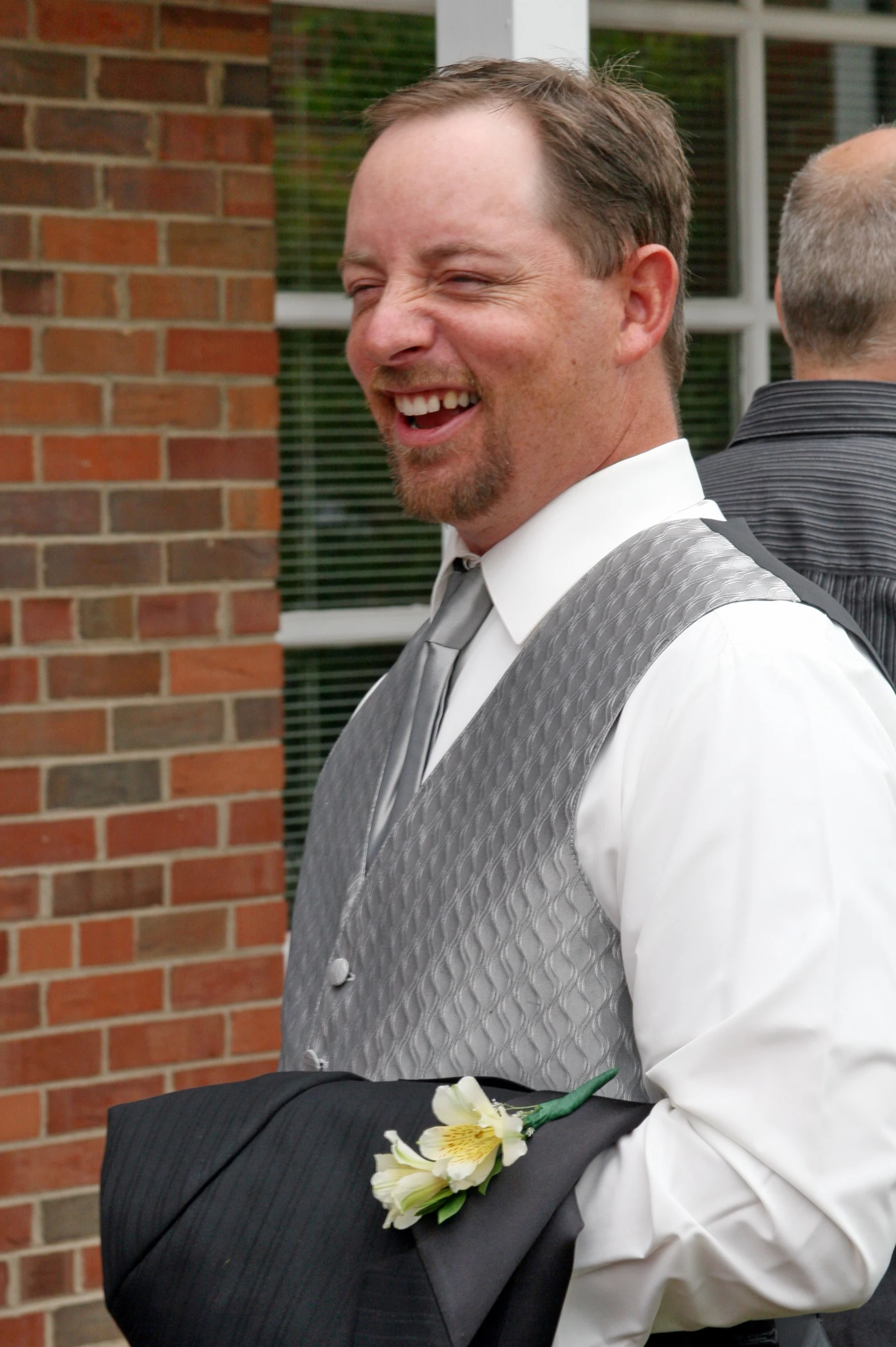 a man smiling in front of a brick building