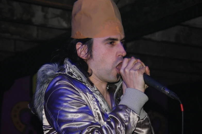 a man in a purple leather jacket is singing with a microphone