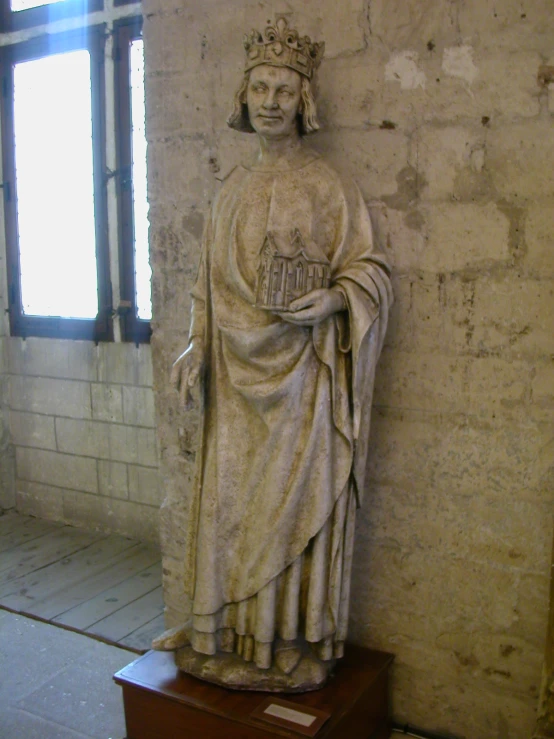 an old statue of jesus is posed by a wall