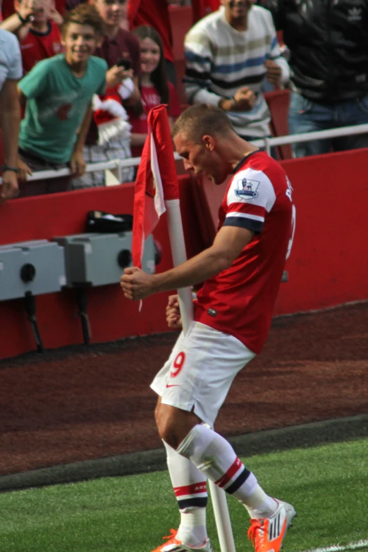 a man wearing an orange and white soccer uniform holds a red and white flag