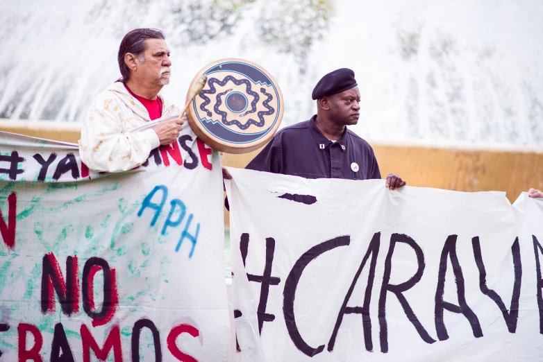 people hold signs and protest against a water fountain