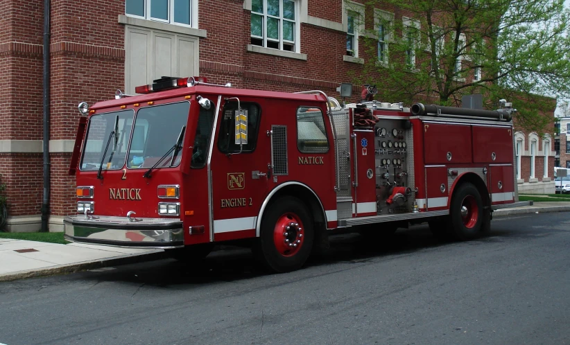 an older firetruck is parked in front of a tall brick building