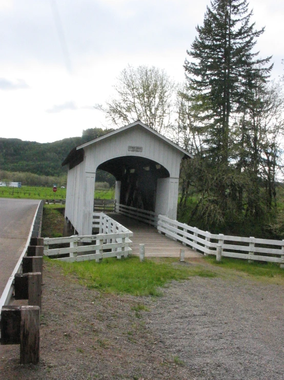 a white wooden covered covered bridge sitting next to a forest