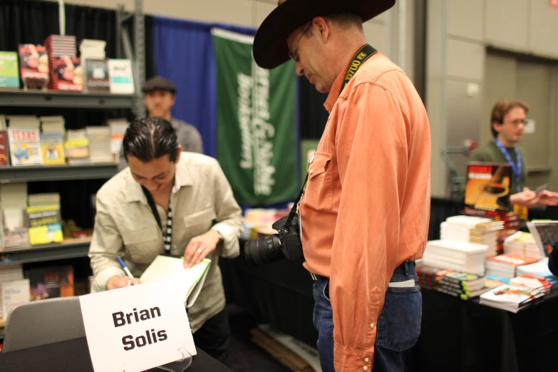 a man standing in a book store signing a paper