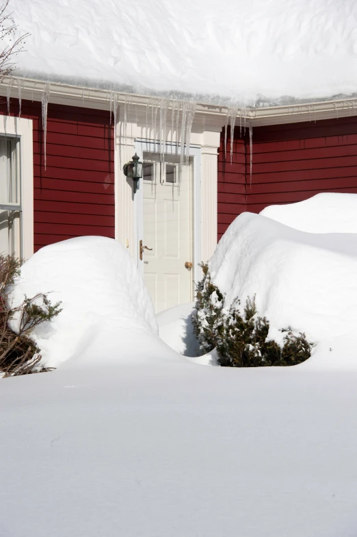 a house that is covered in snow and has ice hanging from it's roof