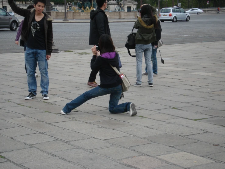 a person kneeling down in front of a woman on a phone