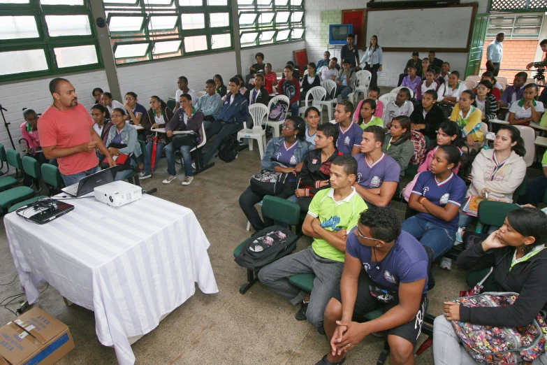 a man speaking to a group of people in chairs