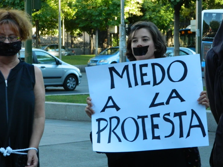 two people standing outside holding a sign that says medd a la proteta