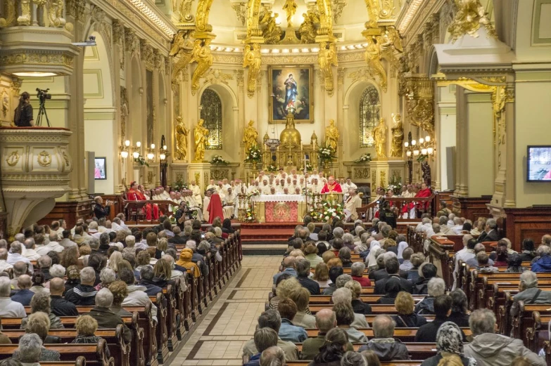 the audience at an ornate catholic church is watching the priest