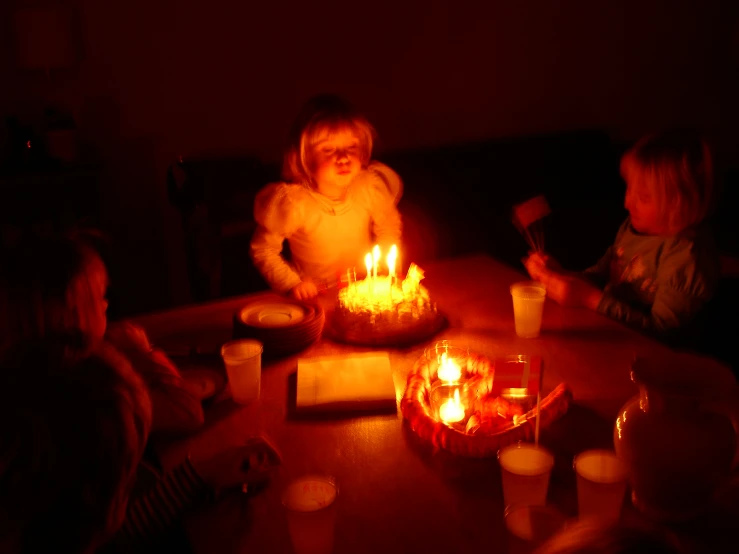 a child in a party is sitting in front of some candles on the table