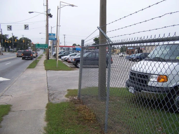 the white truck is parked next to the fence near a street