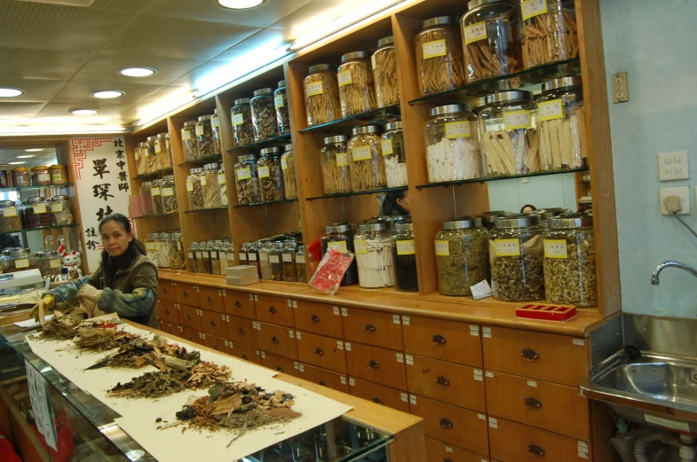 a woman standing behind a counter with various spices