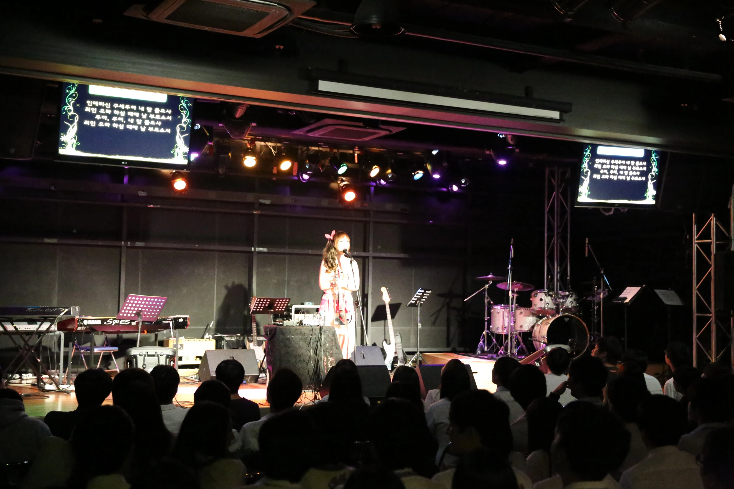 an audience is watching two woman singing on stage