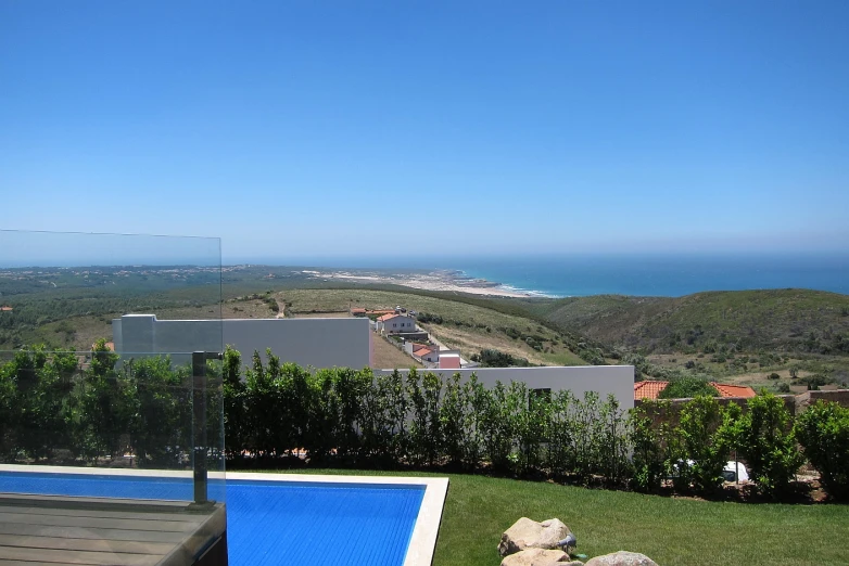 an aerial view of a swimming pool, with the sea and coastline in the background