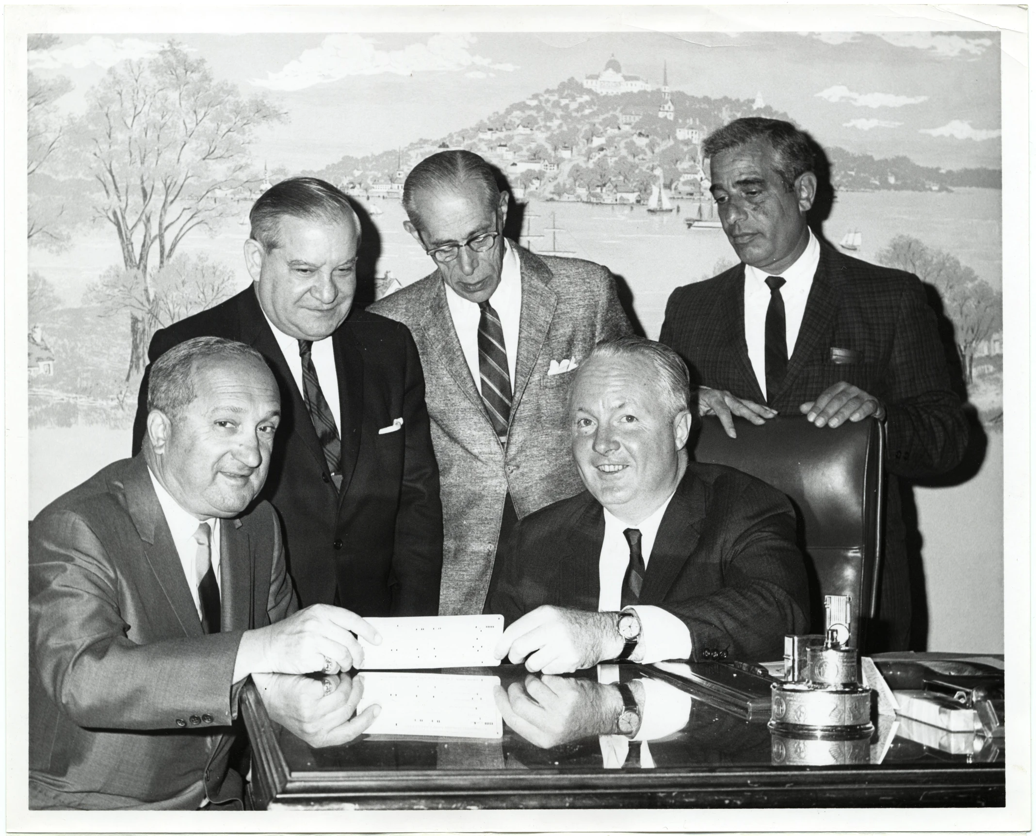 four men pose for a black and white pograph at a desk