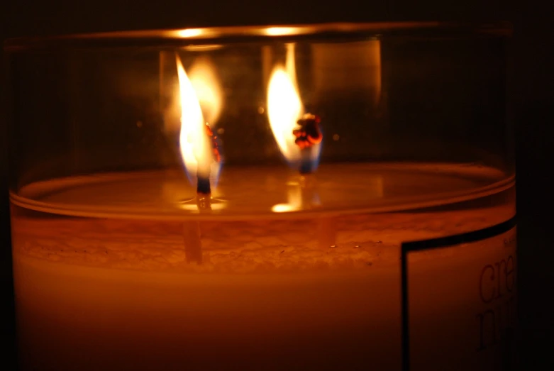 three lit candles burn inside of a glass container