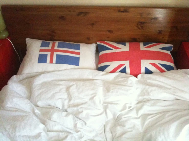 the bed is made with a white comforter, pillows, and the uk flag