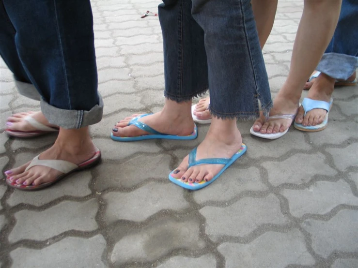 three pairs of people wearing flip flops with two woman with blue toes