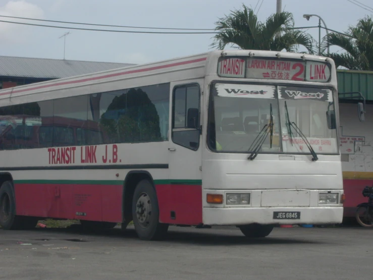 a red and white bus is parked next to a motorcycle