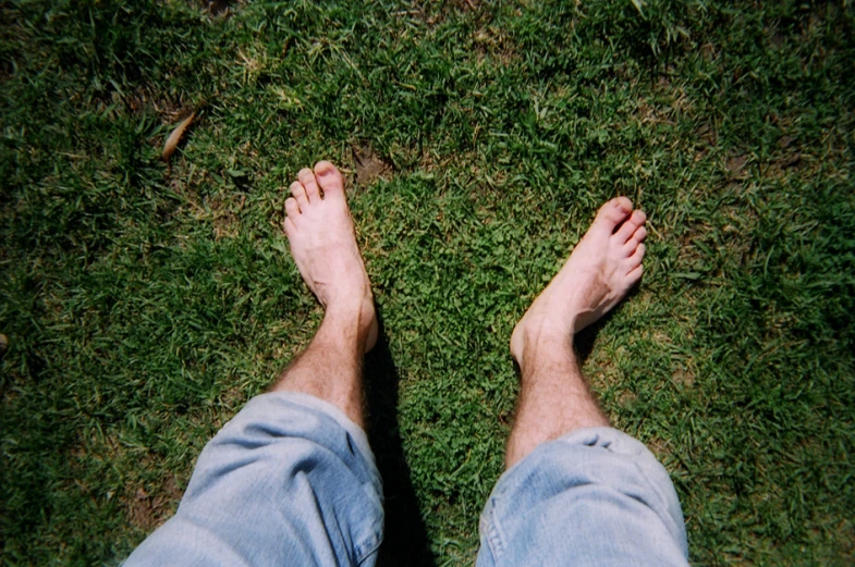 the view from above shows the feet and ankles of a man who is standing in grass