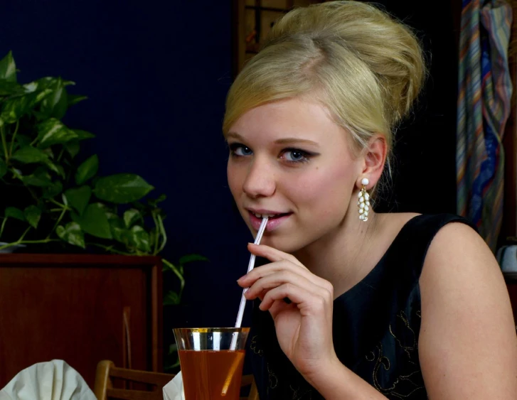 a blonde woman drinking a smoothie at a restaurant