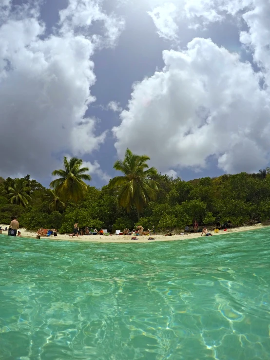 a picture taken from water looking at people on the sand and palm trees