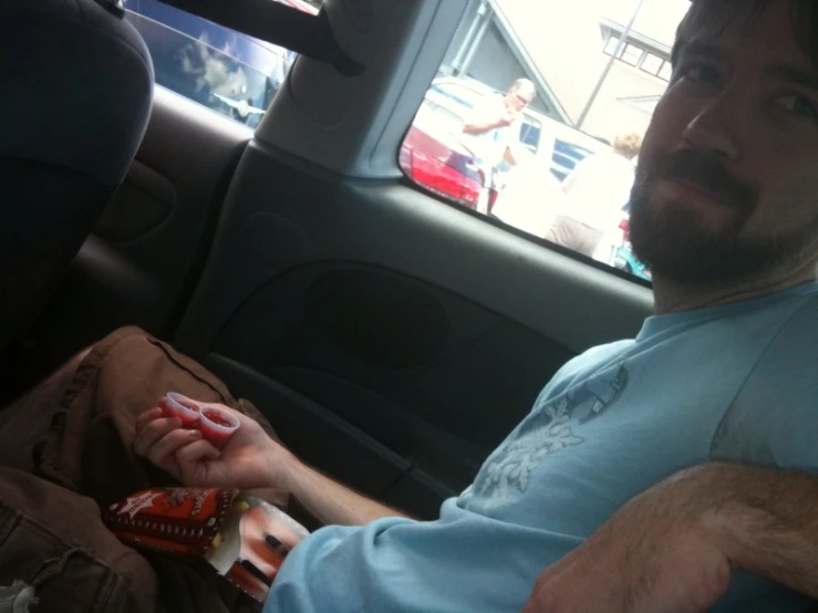 a man holding onto soing in his hands while riding in the back seat of a car