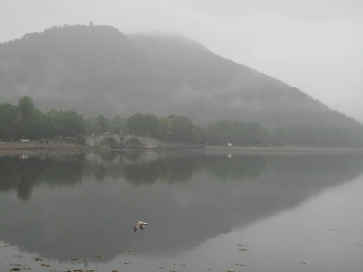 fog shrouds the mountains and river behind a bridge