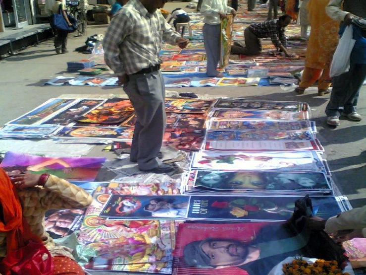 the man in the hat looks at several art work on the ground