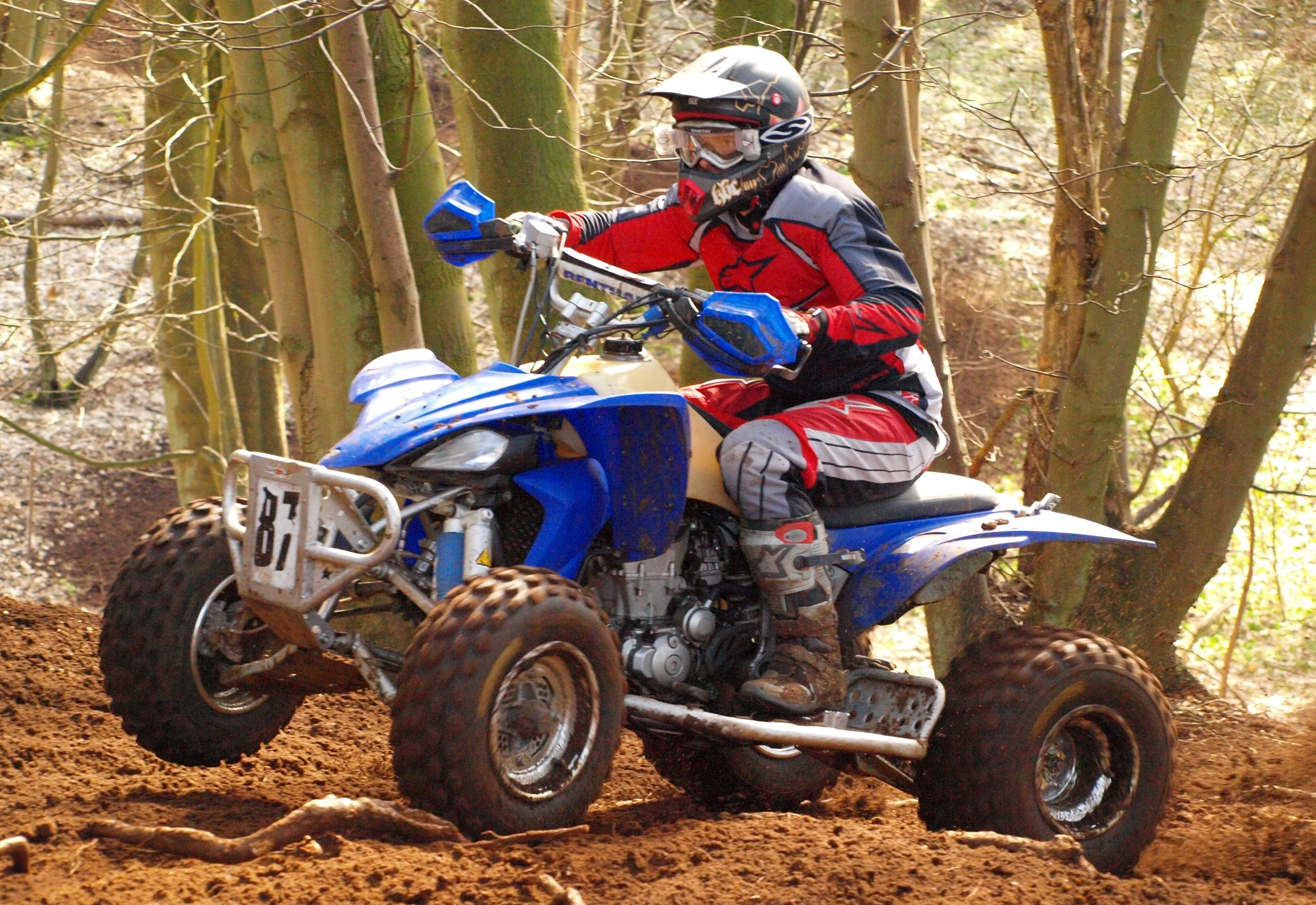 a man riding a blue motorcycle across a forest