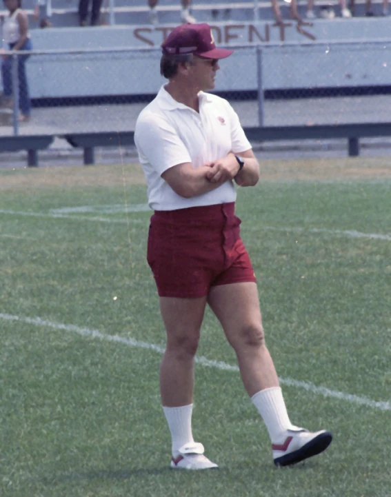 the man in the maroon shorts and white shirt is wearing a maroon hat