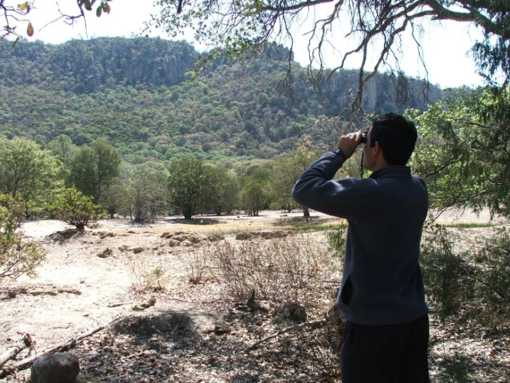 man taking pictures in field with camera in trees