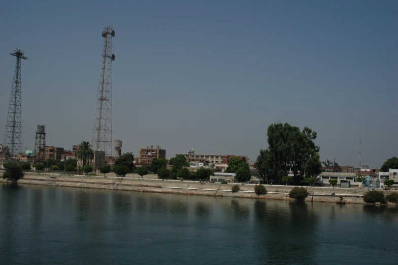 two towers are near water with buildings behind them
