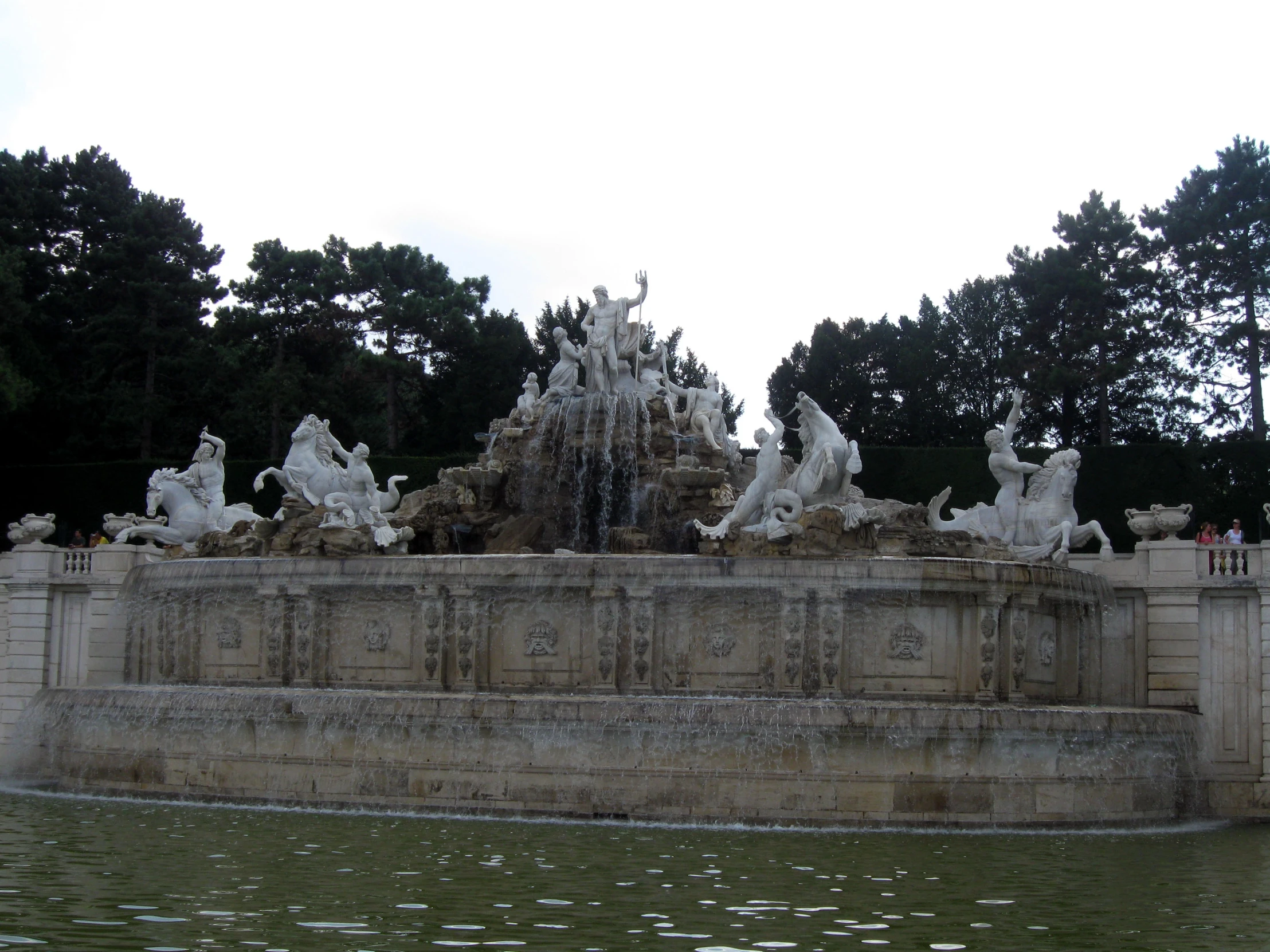 a large fountain sitting next to a park covered in people