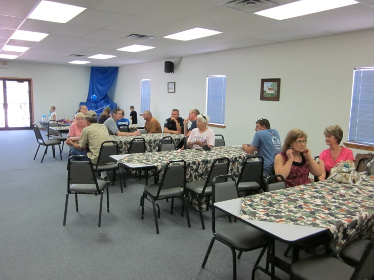 several people sitting at tables looking on from the back