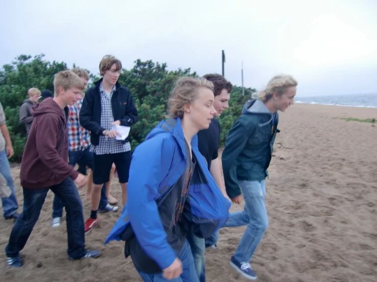 a group of boys walking in the sand on the beach