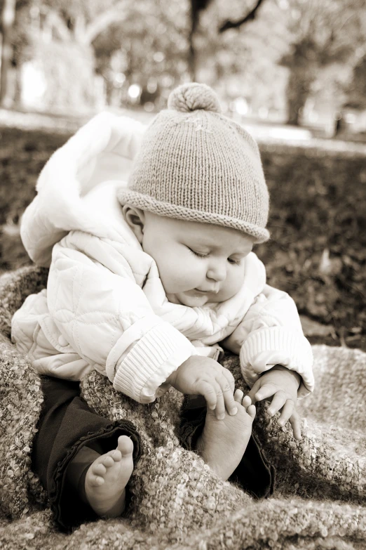 an infant wearing a coat and hat laying on the ground