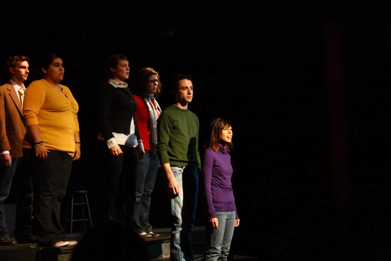 a line of people standing on stage at a performance