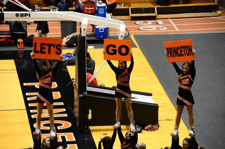 cheerleaders in uniform holding signs up in the air