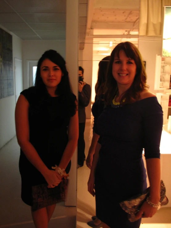 two women in dress standing and smiling in an apartment