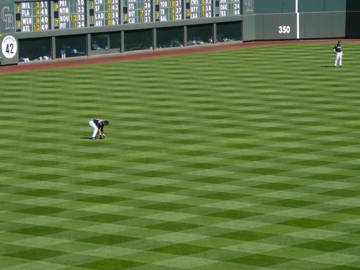 the baseball field is green and has some players playing