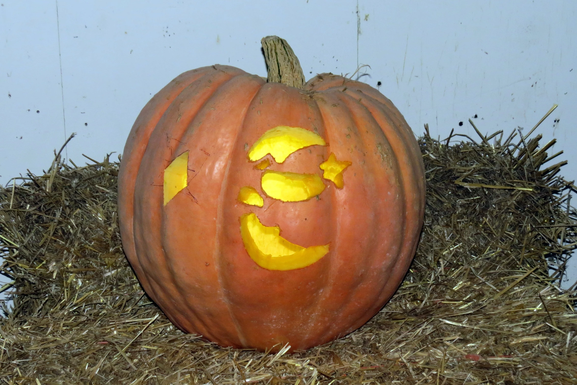 a pumpkin carved to look like a face on hay