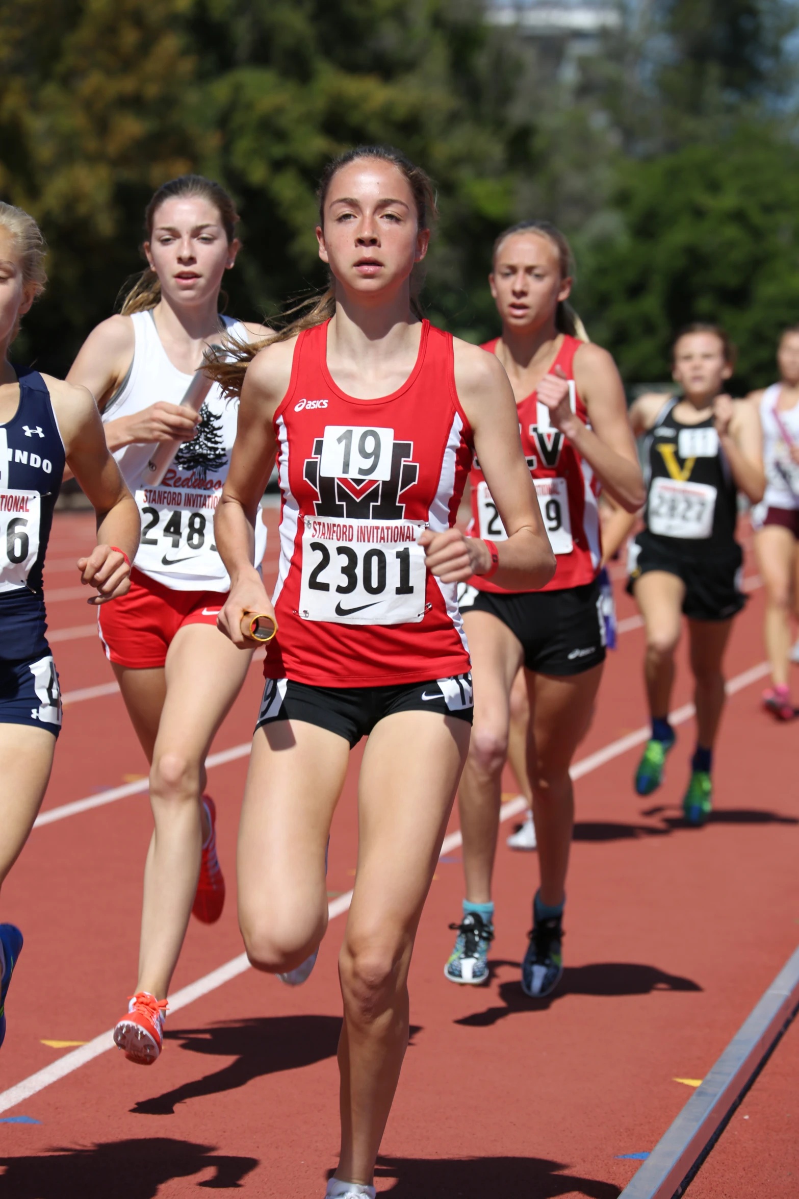 three female athletes are running on a race track